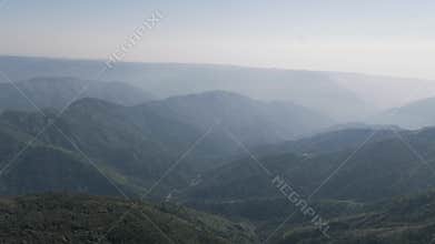 Stunning panoramic aerial view of layered mountains and deep valleys fading into the hazy horizon in the majestic landscape of