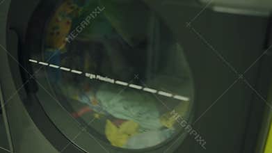 Laundry in Modern Washing Machine in Laundromat - Close-Up View