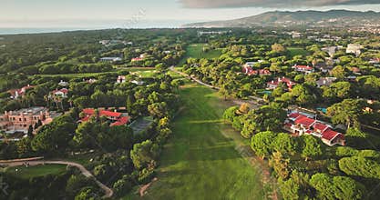 Golf course in Cascais, Portugal, featuring surrounding villas and lush vegetation at sunset