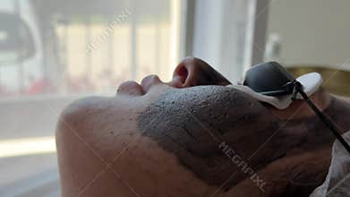Young woman getting carbon laser facial at beauty clinic. Professional skincare