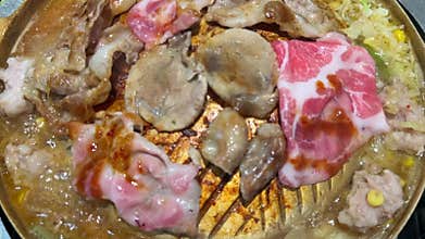 mokrata close up video of Thai BBQ Mookata style, grilling pork and beef on a golden pan.