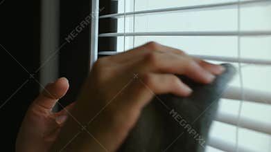 Person cleaning white window blinds with a cloth