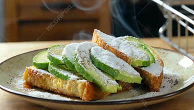 Steaming avocado toast sprinkled with powdered sugar on a plate ready to eat for breakfast or brunch at a cafe or restaurant