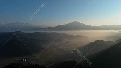 Expansive Dawn Mountain Valley Landscape Shrouded in Mist and Soft Golden Light