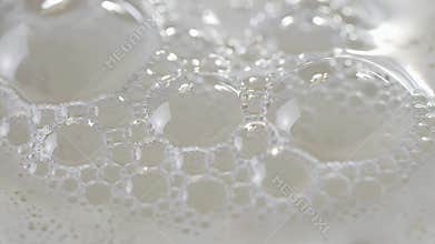 Close-up of fine bubbles forming a frothy, airy layer on a pale liquid surface, captured in macro detail