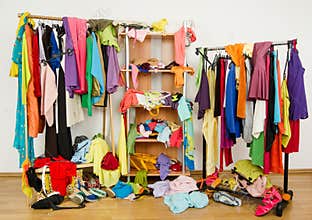 Untidy cluttered woman wardrobe with colorful clothes and accessories.
