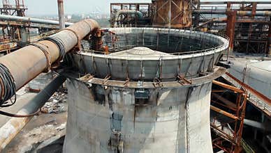 Industrial cooling tower stands tall amidst a complex of pipes and structures outdoors