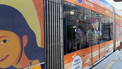 Antalya, Turkey - October 16, 2025: Urban tram approaches station, passengers wait, camera pans to side view