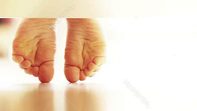 Pair of gently child's feet on the laminate flooring : unusual UNDERbed view