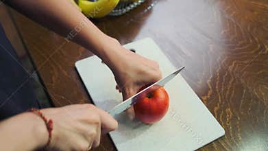 Female hands cut a crisp sweet-sour apple into juicy slices for a healthy snack.
