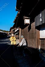 Senior Couple Chatting Outside a Traditional Wooden House in a Historic Japanese Village