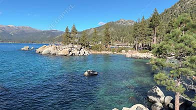 Wide scenic view of Sand Harbor beach cove with emerald water and pine forest background