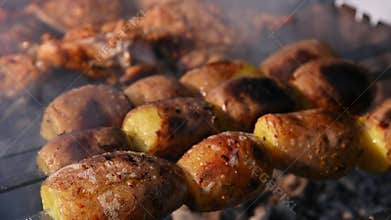 Golden-brown, whole-fried potatoes on skewers. Barbecue cooking over charcoal. Selective focus. Delicious picnic food.