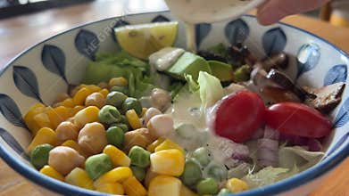 Salad with beans, chickpeas, corn, and tomatoes, topped with black sesame sauce