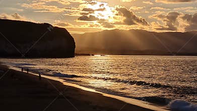 Golden sunset reflects over the atlantic ocean at the volcanic beach of Santa Barbara, Ribeira Grande, Sao Miguel, Azores