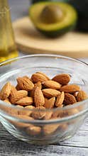 Almonds in a bowl with avocado on a wooden board