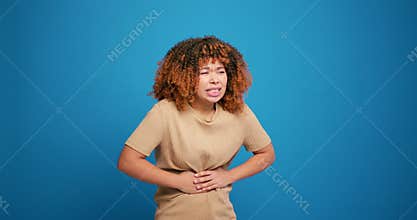 Unhappy, sick hispanic woman having stomach pain, diarrhea isolated on blue background