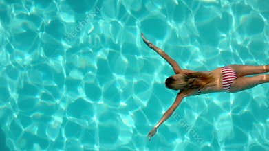 Woman swimming in the pool underwater overhead