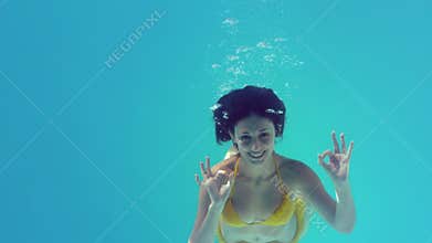 Gorgeous brunette in yellow bikini swimming underwater