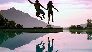 Couple jumping into swimming pool holding hands