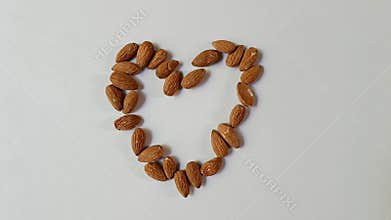 Almonds arranged in heart shape on white background with minimal composition