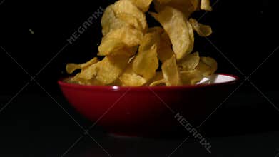 Chips falling into bowl on black surface