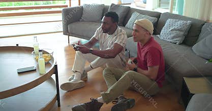 Diverse male friends starting match with controllers eating chips, sipping lemonade in living room