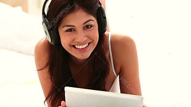 Brunette woman using a tablet pc while listening to music
