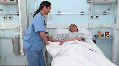 Nurse assisting a patient to lie down in a medical bed