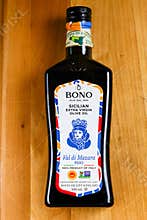 500ml glass bottle of Bono Sicilian Extra Virgin Olive Oil on a rustic wooden cutting board.