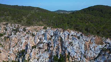 Hikers exploring rocky cliff face in Ibiza. Magic aerial view flight drone