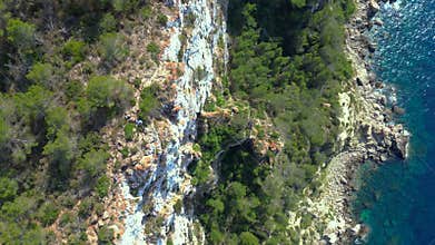 Hikers exploring rocky cliff face in Ibiza. Wonderful aerial view flight drone