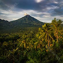 Tall active volcano seen in distance covered with green lush tropical rainforest in flores island, Indonesia