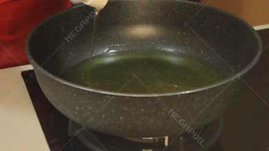 Pour cooking oil into the pan. One fills a frying pan with cooking oil