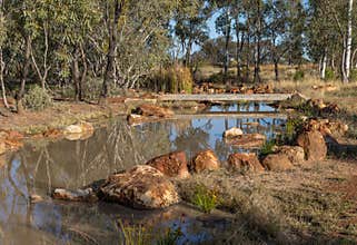 A wetland pond crossed by a bridge and surrounded with rocks in outback Australia.