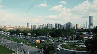 Cityscape view with modern skyscrapers, busy roads, traffic, buses and green areas under a partly cloudy sky. Belgrade, Serbia -