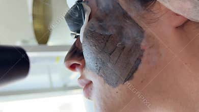Young woman getting carbon laser facial at beauty clinic. Professional skincare