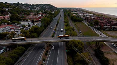 Aerial Drone View of urban highway with buses Crossing Overpass and Coastal City at Sunset