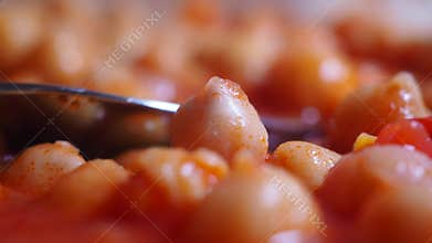 Cooking chickpeas in spicy tomato sauce with fresh herbs