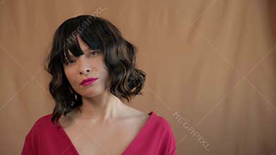 Beautiful fashionable brunette woman with trendy bob haircut, wavy dark hair with bangs, wearing bright make-up and red lipstick