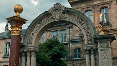 Architectural archway with golden accents and candle holder adorns a historic building facade