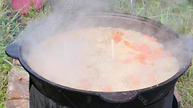 rice and carrots are cooked in a cauldron