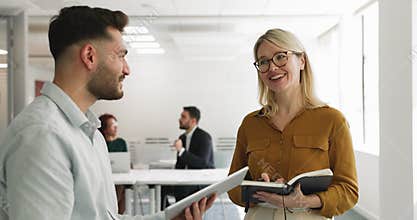 Couple of happy business colleagues talking in office
