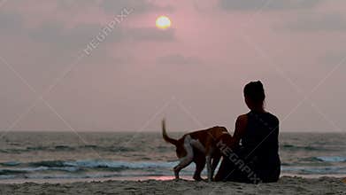 Woman hugs her dog at sunset