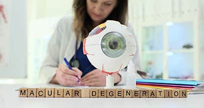 Wooden blocks spell phrase Macular Degeneration near eye model