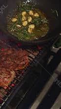 close-up footage of grilling steaks, barbecue party in evening, the meat is stewed in butter with garlic and thyme