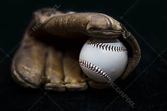 Baseball in a glove with black background