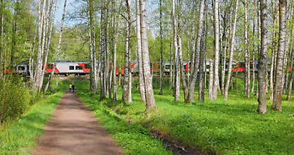 Russia, St.Petersburg, The passenger electric train goes nearby summer park, train of the Russian Railway company