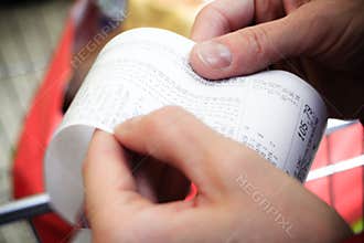 Supermarket. paper check receipt bill in hand.