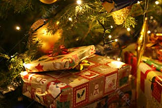 Christmas gifts brought by Santa Claus lying under the lit Christmas tree.
